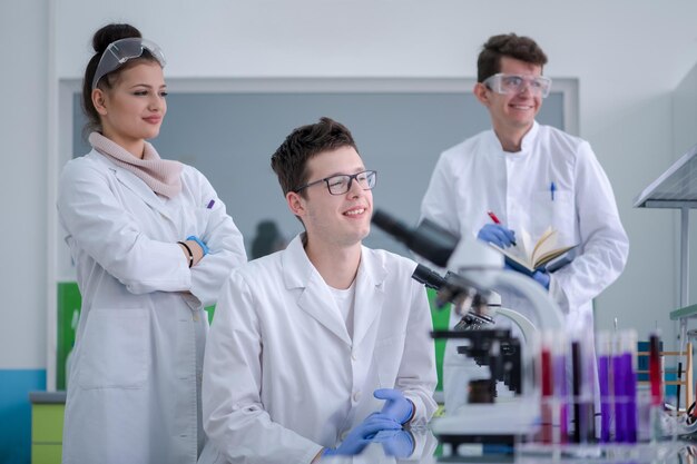 Gruppo di giovani studenti di medicina che fanno ricerca insieme nel laboratorio di chimica, lavoro di squadra di studenti universitari al chiuso