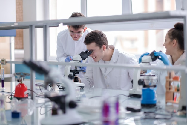 Gruppo di giovani studenti di medicina che fanno ricerca insieme nel laboratorio di chimica, lavoro di squadra di studenti universitari al chiuso