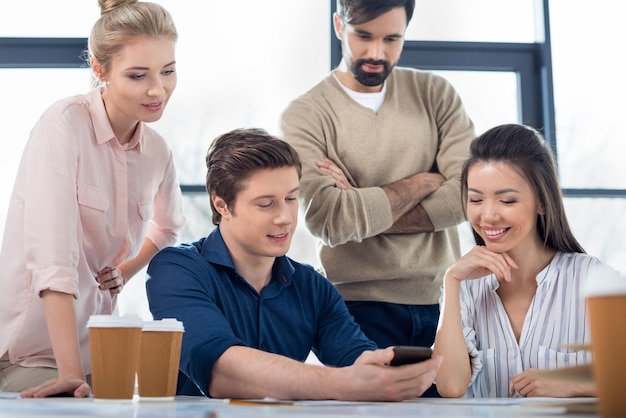 Gruppo di giovani uomini d'affari che utilizzano lo smartphone durante una riunione di piccole imprese