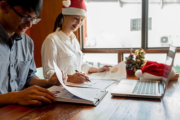 Gruppo di giovani uomini d&#39;affari festeggiano sul posto di lavoro con cappelli di Babbo Natale