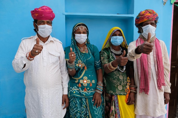 Gruppo di indiani in costumi nazionali che indossano maschere facciali durante la pandemia COVID-19