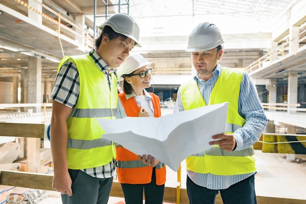 Gruppo di ingegneri, costruttori, architetti sul cantiere, guardando nel progetto