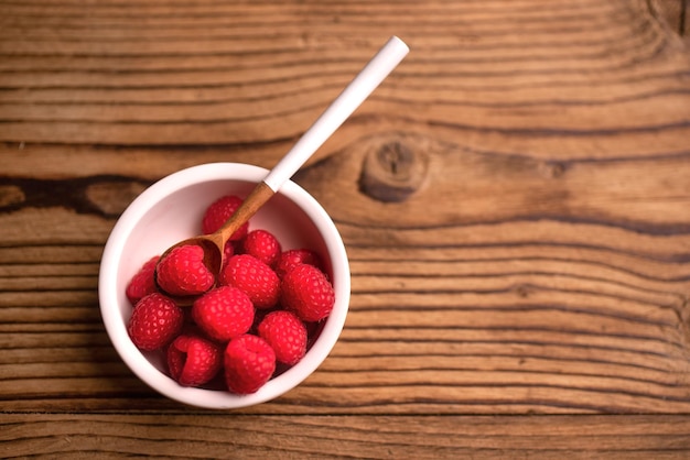 Gruppo di lamponi in una ciotola bianca. Uno stile di vita sano. Frutta fresca.