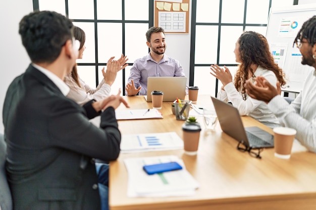 Gruppo di lavoratori che sorridono e applaudono il loro partner in ufficio