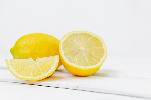 Gruppo di limoni: interi, metà e una fetta su un muro bianco. Spazio per il testo. Vitamine e una dieta sana.