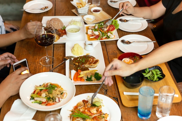 Gruppo di mani di amici con la forcella divertirsi mangiando cibo varietà sul tavolo.