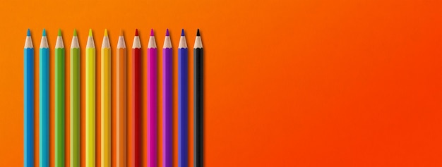Gruppo di matite colorate isolato su arancione Sfondo banner panoramico