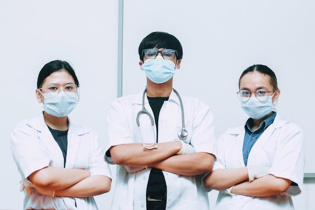 Gruppo di medico che indossa maschera protettiva e uniforme in posa con fiducia