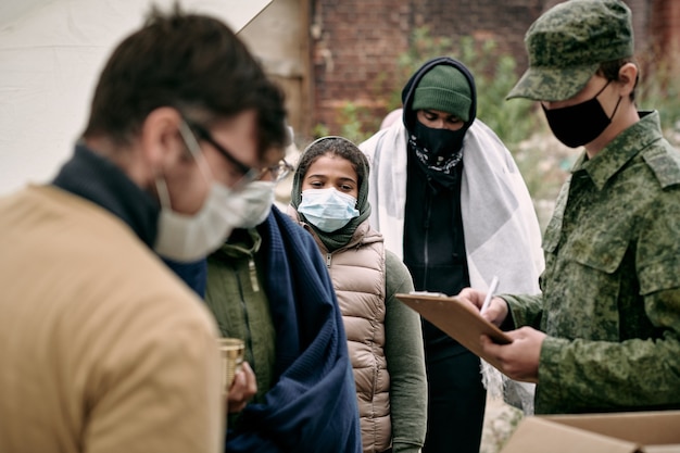 Gruppo di migranti con mascherine protettive in attesa di donazione