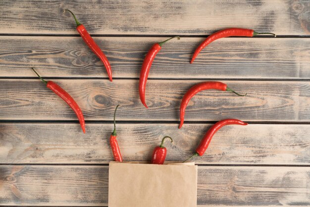 Gruppo di peperoncini rossi su tavolo in legno sbiadito vista dall'alto Peperoncini piccanti da togliere dal sacchetto di carta ecologica Cibo biologico o concetto di dieta sana Posizione separata degli oggetti in ordine Planking