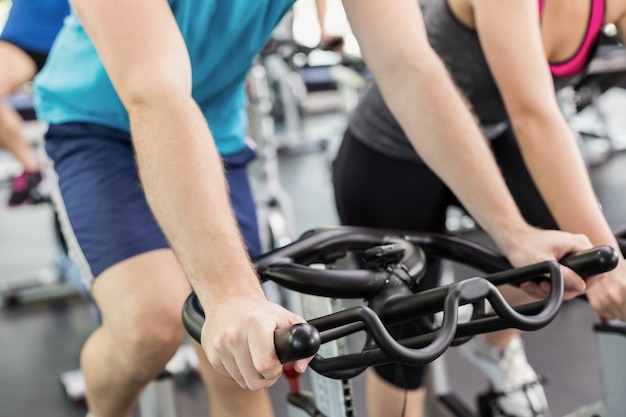 Gruppo di persone adatto facendo uso della bici di esercizio insieme in palestra