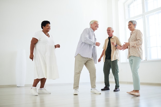Gruppo di persone anziane che si divertono e ballano insieme nello studio di danza