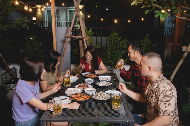 Gruppo di persone asiatiche che cenano nel giardino di casa in vacanza Celebrazione della festa in giardino serale estiva con gli amici