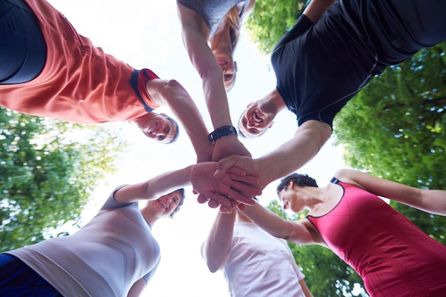 gruppo di persone che fanno jogging, gli amici si divertono, abbracciano e impilano le mani insieme dopo l'allenamento