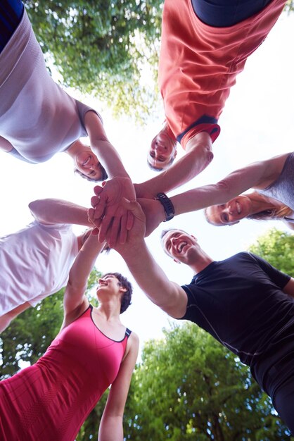 gruppo di persone che fanno jogging, gli amici si divertono, abbracciano e impilano le mani insieme dopo l'allenamento