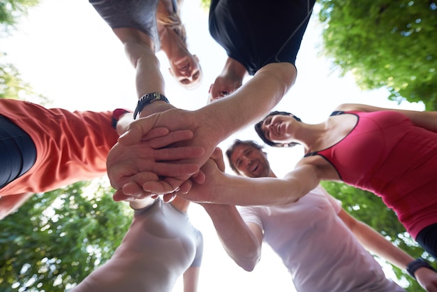 gruppo di persone che fanno jogging, gli amici si divertono, abbracciano e impilano le mani insieme dopo l'allenamento