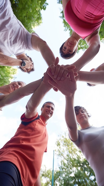 gruppo di persone che fanno jogging, gli amici si divertono, abbracciano e impilano le mani insieme dopo l'allenamento