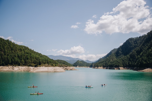 Gruppo di persone che fanno kajak su un lago dell'acqua blu nelle montagne un giorno soleggiato di estate