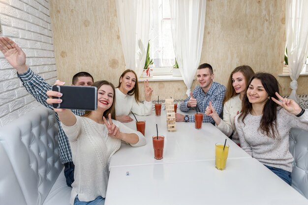 Gruppo di persone che giocano a torre al bar e si fanno selfie