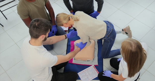 Gruppo di persone che imparano a eseguire compressioni cardiache di primo soccorso con manichini durante l'allenamento al chiuso.