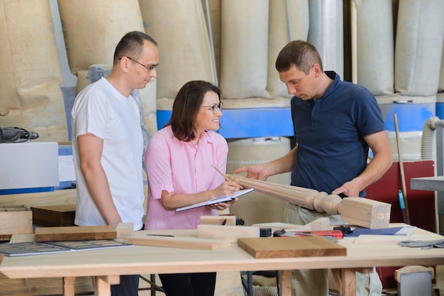 Gruppo di persone che lavorano per discutere del processo di lavoro, prodotti in legno nel laboratorio di falegnameria