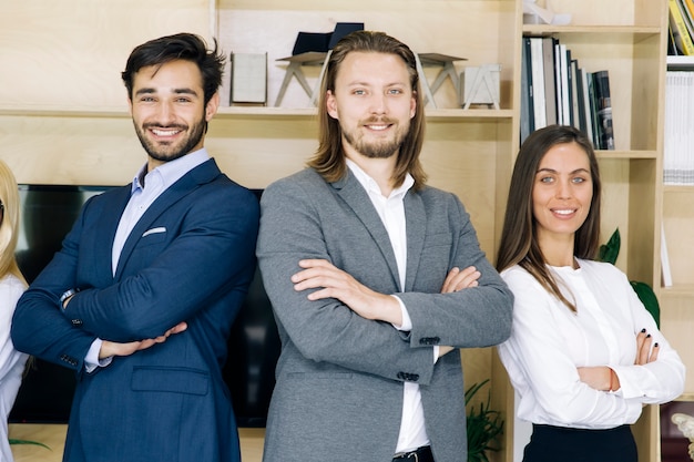 Gruppo di persone di affari amichevoli in vestiti che si levano in piedi all&#39;ufficio