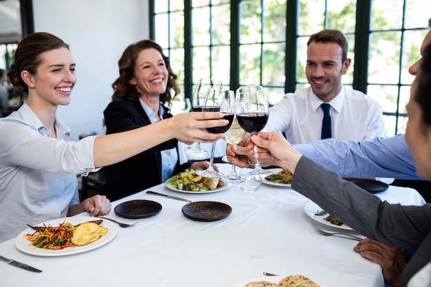 Gruppo di persone di affari che tostano il bicchiere di vino durante la riunione del pranzo di lavoro