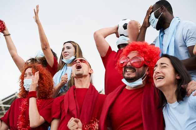 Gruppo di persone di razze diverse che rallegrano la loro squadra allo stadio di calcio