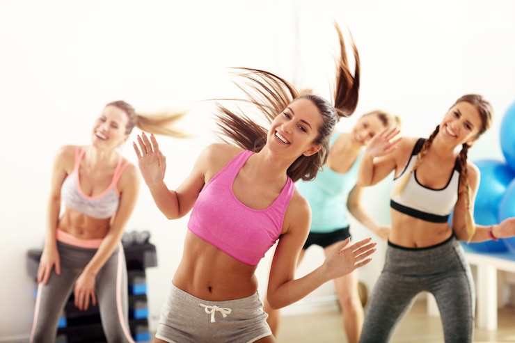 Gruppo di persone energiche con allenatore che balla in palestra