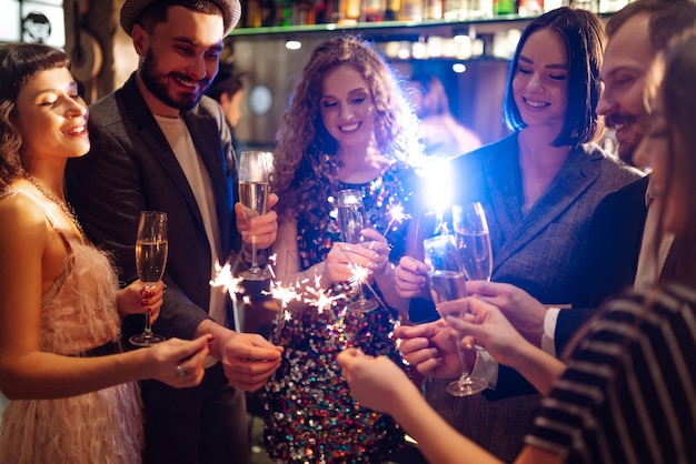 Gruppo di persone felici che tengono le stelle filanti alla festa. Giovani amici tintinnano bicchieri di champagne.