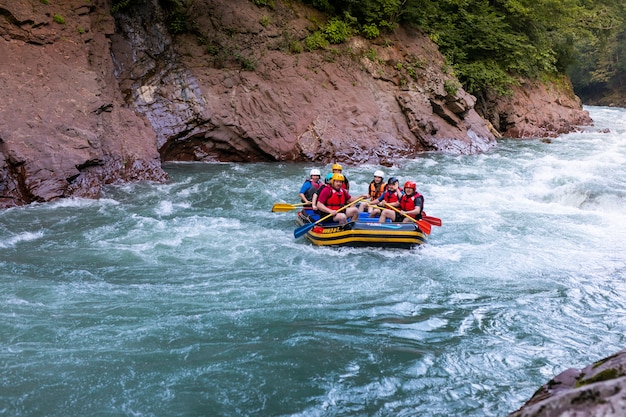 Gruppo di persone felici con guida rafting e canottaggio sul fiume.