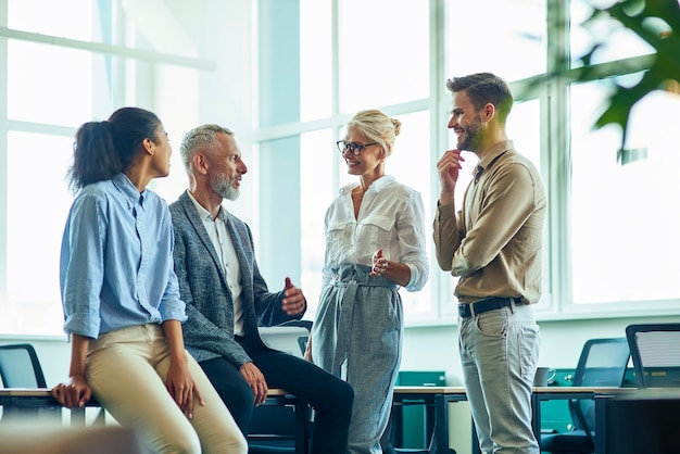 Gruppo di persone multirazziali di successo che comunicano e discutono di affari stando in piedi nel