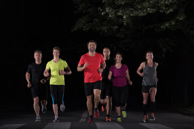 gruppo di persone sane jogging nel parco della città, squadra di corridori di formazione notturna