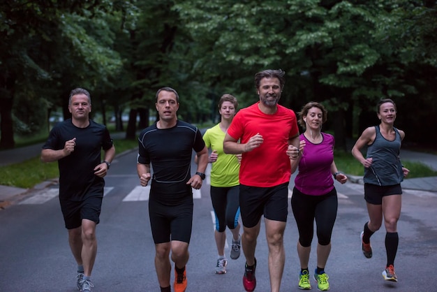 gruppo di persone sane jogging nel parco della città, squadra di corridori sulla formazione mattutina