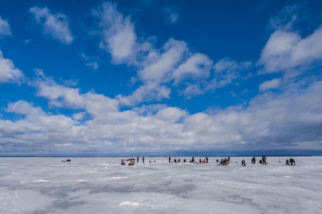 Gruppo di pescatori degli uomini che pescano in inverno sul ghiaccio del fiume