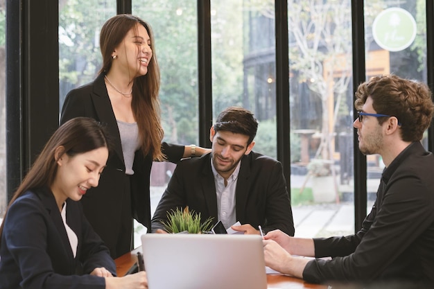 Gruppo di professionisti aziendali, team di giovani asiatici, caucasici che lavorano e comunicano, analizzano i dati, discutono, utilizzano il computer portatile spiegano il nuovo progetto con i colleghi sul posto di lavoro.