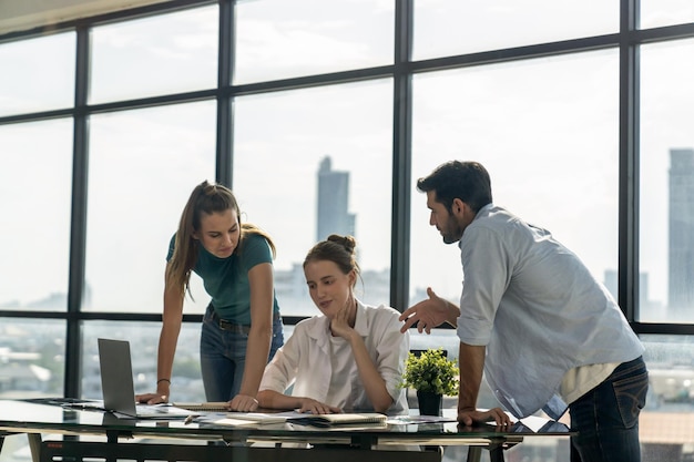 Gruppo di professionisti di business team brainstorming idea di marketingGiovane bella manager guardando il portatile mentre ascolta collega di lavoro condivisione idea a riunione Lavorare insieme Skyscraper vista Tracery