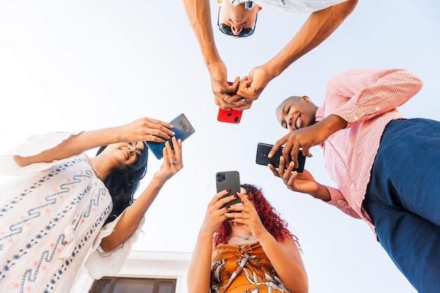 Gruppo di quattro amici insieme utilizzando gli smartphone