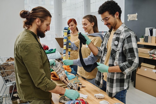 Gruppo di quattro volontari interculturali che smistano vestiti di seconda mano