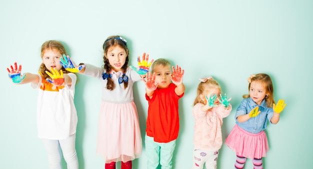 Gruppo di ragazzi giovani artisti che presentano sulla fotocamera i loro palmi multicolori. I bambini dopo le lezioni sulla pittura con le dita alla scuola creativa.