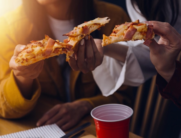 Gruppo di risate di diverse giovani donne che escono insieme a casa e mangiano pizzaxALGruppo di risate di diverse giovani donne che escono insieme a casa e mangiano pizzaxAxA