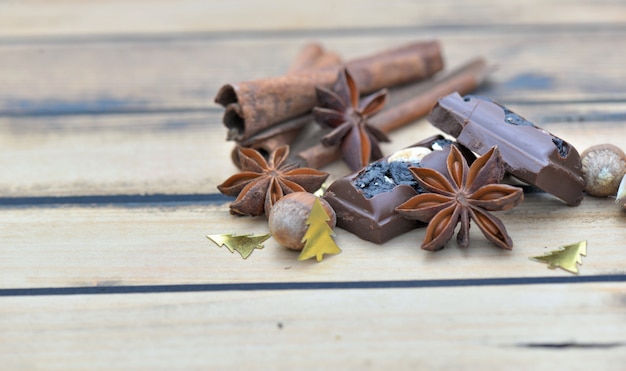 Gruppo di spezie e cioccolato con i coriandoli di natale su una tavola di legno