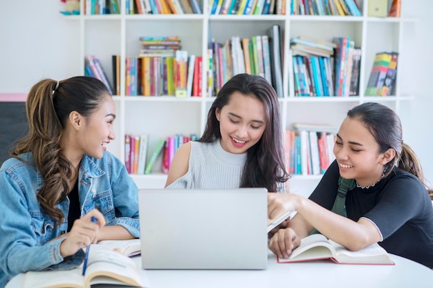 Gruppo di studentesse che usano un portatile in biblioteca