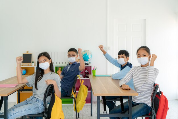 Gruppo di studenti asiatici della scuola elementare che indossano maschera igienica