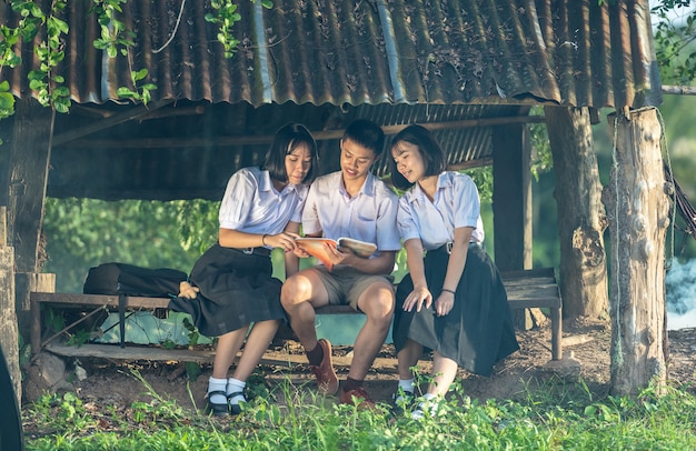 Gruppo di studenti asiatici in uniforme studiando insieme all&#39;aperto.