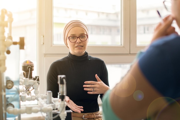 Gruppo di studenti che fanno pratica tecnica professionale con una giovane insegnante musulmana nell'aula elettronica, concetto di istruzione e tecnologia