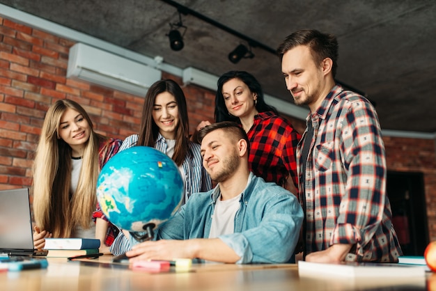 Gruppo di studenti delle scuole superiori che guardano il globo, progetto di lavoro di squadra.