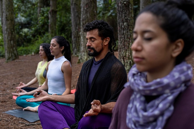 Gruppo di studenti di yoga che meditano nella foresta