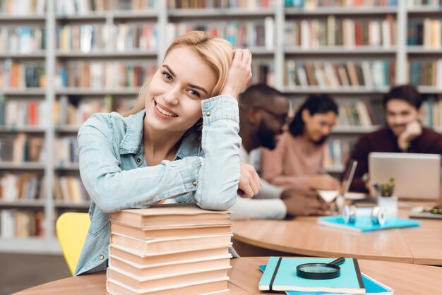 Gruppo di studenti etnici multiculturali in biblioteca. Ragazza bianca con libri.