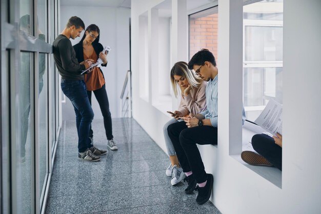 Gruppo di studenti in corridoio con documenti e telefoni cellulari